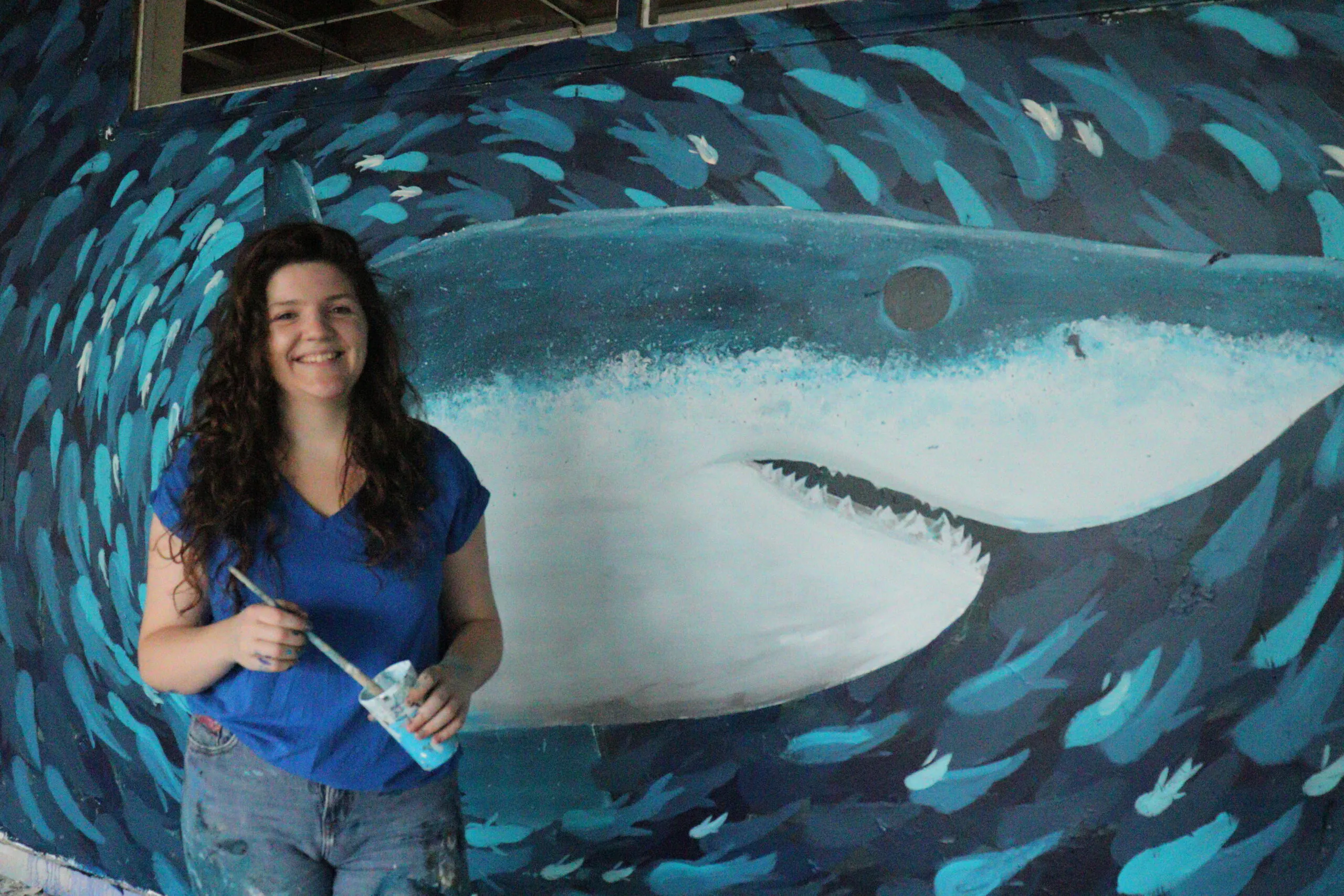 L'artiste pose devant sa fresque murale représentant un requin