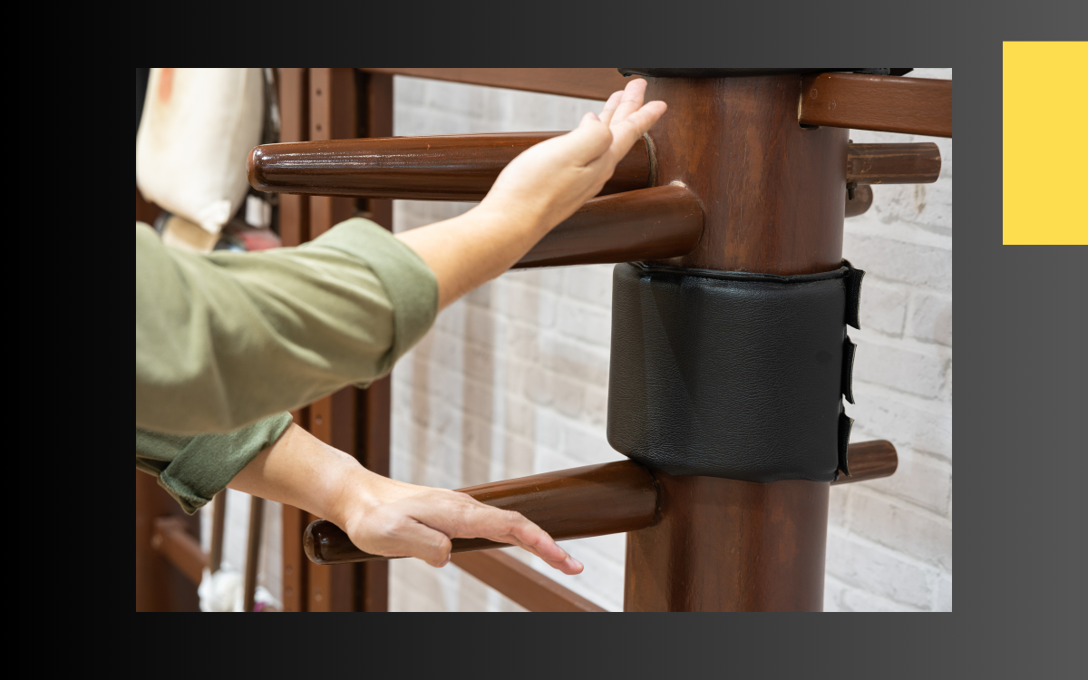 Des mains sont posées sur un mannequin de bois de wing chun