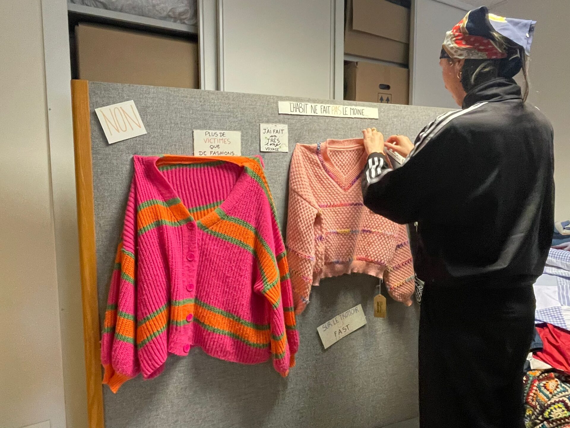 Charlotte travaillant sur un panneau d'affichage qui explique la composition d'un vêtement de fast-fashion à côté d'un vêtement de slow-fashion